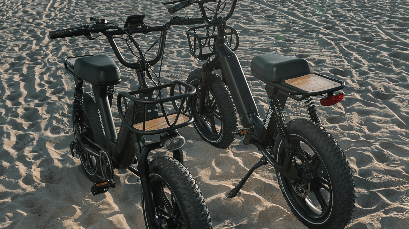 Two Himiway Electric bikes standing on a sand.