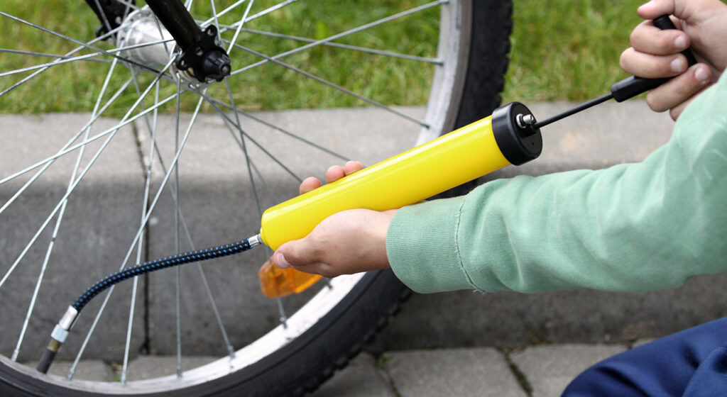 young person using a bicycle pump to inflate his ebike tire